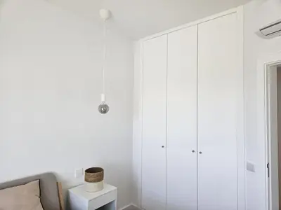 a living room with a large white cabinet at Apartamento moderno com vista para o mar em Faro in Faro