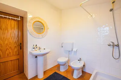 a bathroom with a sink and a toilet and a mirror at Quinta da Bisa - Casa das Pedrinhas in Algoz