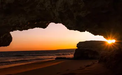 a sunset seen through an opening in a cave on the beach at Modern Apartment in Albufeira in Albufeira