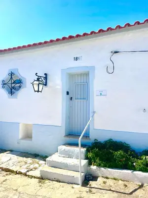 a white building with a blue door and stairs at Toca das Manas in Roja- Pé