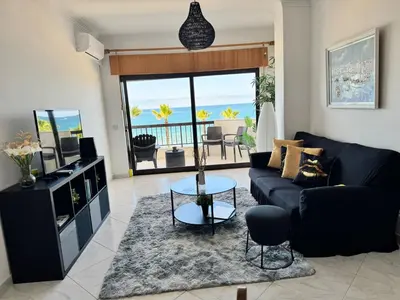 a living room with a black couch and a television at Adrimar - Beachfront Sea View 2BR Apartment in a prime location in Quarteira