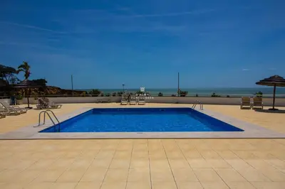 a swimming pool with the ocean in the background at Apartamento Varandas do Mar in Albufeira