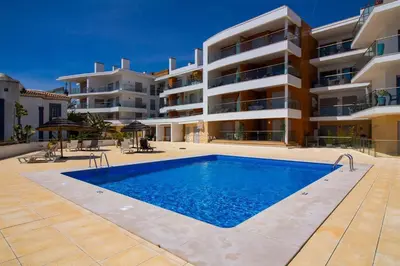 an apartment with a swimming pool in front of a building at Apartamento Varandas do Mar in Albufeira