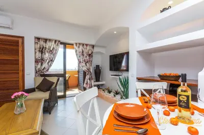 a dining room and living room with a table and chairs at Clementina Apartment in Albufeira