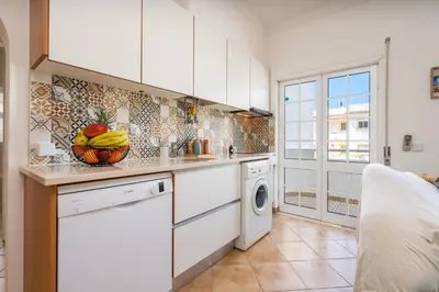 a kitchen with white cabinets and a dishwasher at Sunny Flat w/ Balcony near the Sea by HostWise in Albufeira