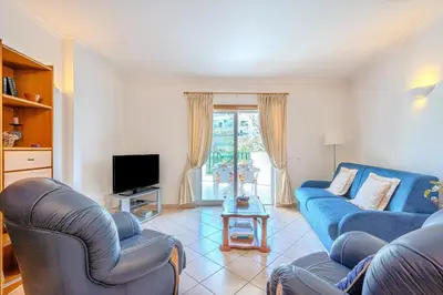 a living room with a blue couch and a tv at Apartmento Estrela de Albufeira Old Town Beach in Albufeira