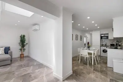 a white living room with a table and a kitchen at Amazing Oura Beach Apartment in Albufeira