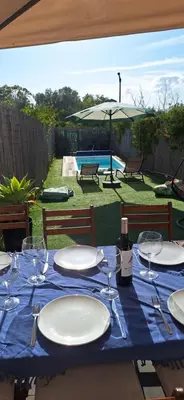 a table with wine glasses and an umbrella at Casa do Baco - Private Pool in Quarteira