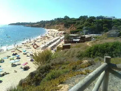 a beach with people laying on the sand and the water at Vacances Tranquilles in Olhos de Água