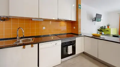 a kitchen with white cabinets and an orange tile wall at Apartamento Studio Sao Rafael, 450m Praia in Albufeira