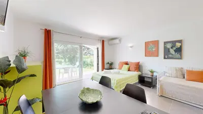 a living room with a bed and a room with a table at Apartamento Studio Sao Rafael, 450m Praia in Albufeira