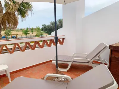 a kitchen and living room with a counter and chairs at Palmeira Home in Olhos de Água