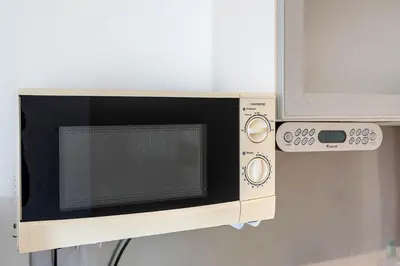 a microwave oven is attached to a wall at Blife Riamya private rooms in Faro