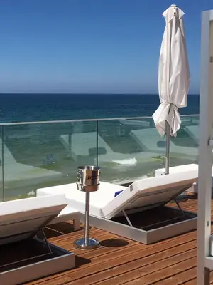 a balcony with a table and an umbrella and the ocean at Serenity-First villa in Albufeira