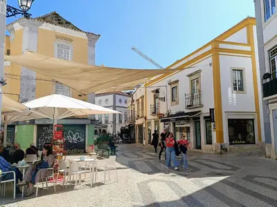 a group of people walking down a street with buildings at Grey and Green, modern 2-bedroom apartment, AC, top location at faro's historic centre in Faro
