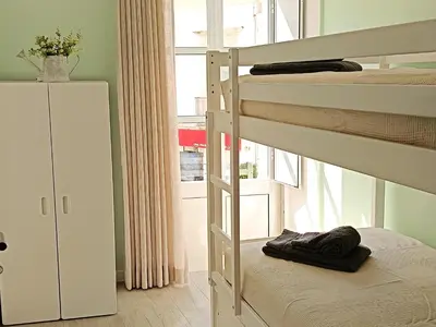 a bedroom with two bunk beds and a window at Grey and Green, modern 2-bedroom apartment, AC, top location at faro's historic centre in Faro