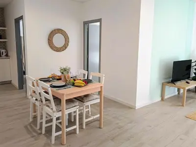 a dining room table with chairs and a television at Grey and Green, modern 2-bedroom apartment, AC, top location at faro's historic centre in Faro