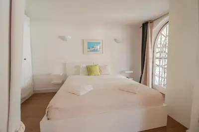 a white bedroom with a large bed with a window at Old Village - Vilamoura T0 com pátio in Bicas