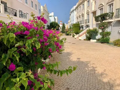 a cobblestone street with pink flowers in front of buildings at Old Village - Vilamoura T0 com pátio in Bicas