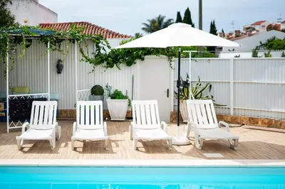 four white chairs and an umbrella next to a pool at Maison Du Soleil by Seareen in Albufeira