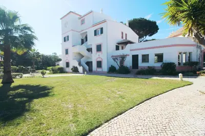 a large white building with a grass yard at Solar do Golf T1 Vilamoura Old Village in Quarteira