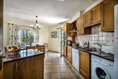 a kitchen with wooden cabinets and a dishwasher at Rebela 1st Algarve Villa Holidays in Albufeira
