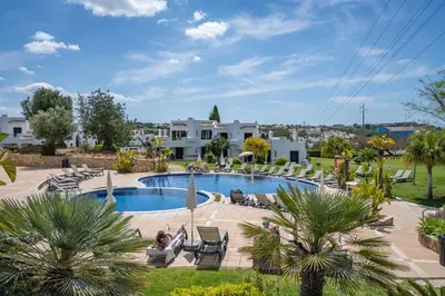 a pool with chairs and trees and houses at Sunny Flat with a Balcony & Pool by HostWise in Albufeira