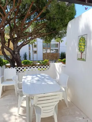 a white table and chairs on a patio with a tree at Balaia Golf Village 122 in Albufeira