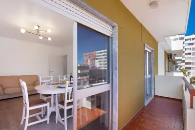 a white kitchen with white cabinets and a table at Justo's House in Faro
