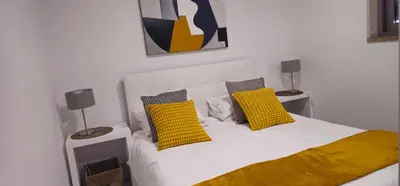 a white bed with two yellow pillows on it at Casa dos Sinos Beach Apartment 1 with Roof Terrace in Albufeira