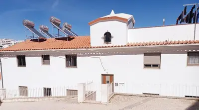 a white building with a red roof with birds on the roof at Casa dos Sinos Beach Apartment 1 with Roof Terrace in Albufeira