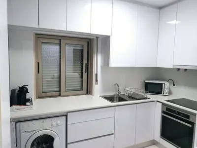 a white kitchen with a sink and a dishwasher at Casa dos Sinos Beach Apartment 1 with Roof Terrace in Albufeira