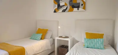 a bedroom with two beds and a painting on the wall at Casa dos Sinos Beach Apartment 1 with Roof Terrace in Albufeira