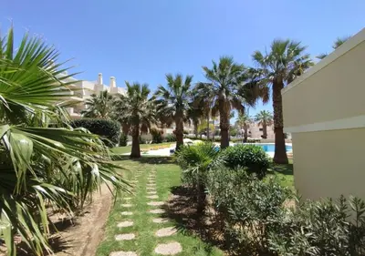 a garden with palm trees and a swimming pool at São rafael Ocean View in Albufeira