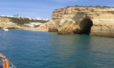 a boat in the water next to a cave in a cliff at São rafael Ocean View in Albufeira