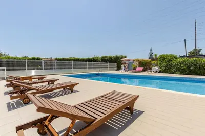 a row of wooden benches next to a swimming pool at Maison A Quinta V2A 5 Personnes in Ferreiras