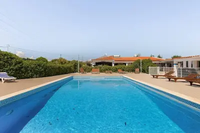 a large blue swimming pool with benches and a house at Maison A Quinta V2B 7 Personnes in Ferreiras