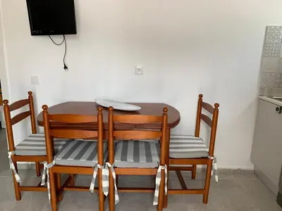 a dining room table with four chairs and a television at Açoteias Falésia Studio Apartment in Olhos de Água