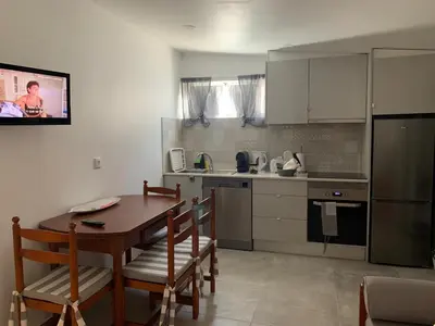 a kitchen with a table and chairs and a kitchen with a tv at Açoteias Falésia Studio Apartment in Olhos de Água