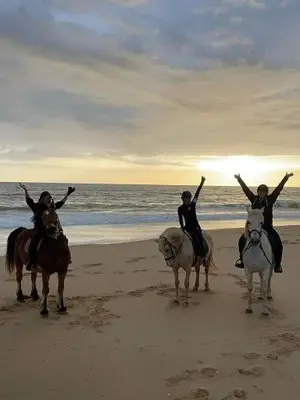 two people riding horses on the beach with their arms up at Stork nest in Vilamoura