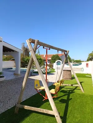 a swing set with two chairs in a yard at Villa Inês in Guia