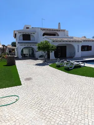 a large white house with a patio with lawn chairs at Villa Inês in Guia