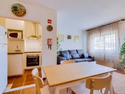 a kitchen and living room with a table and a couch at Apartamento Forte Novo no centro de Quarteira in Quarteira