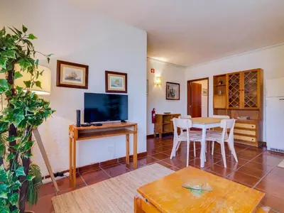a living room with a table and a tv at Apartamento Forte Novo no centro de Quarteira in Quarteira