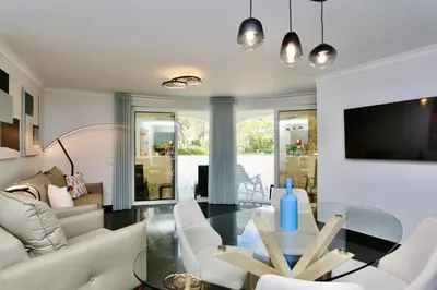 a living room with a glass table and white chairs at Monte Verde A,Lar Linda - CD 293 Cleverdetails, Sleeps 2 adults and 2 children, 4 salted water pools in Quarteira
