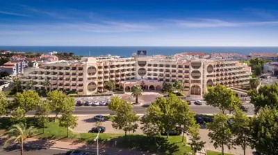 a large building with a parking lot in front of the ocean at Hotel Vila Galé Cerro Alagoa in Albufeira