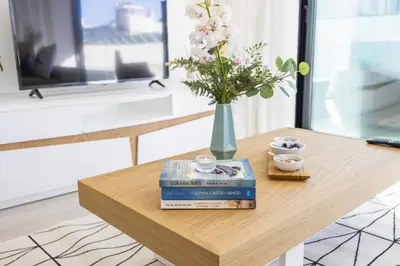 a wooden table with books and a vase with flowers at Terracos de Quarteira Orange by Real Properties in Quarteira