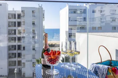 a table with a bottle of wine and a bowl of fruit at Terracos de Quarteira Orange by Real Properties in Quarteira