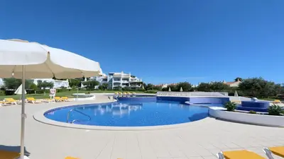 a large swimming pool with an umbrella and chairs at Monte Verde B CD 294 - Cleverdetails, Sleeps 2 adults and 2 children, 4 salted water pools in Quarteira