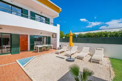 a patio with white chairs and an umbrella at Villa Lamella in Albufeira